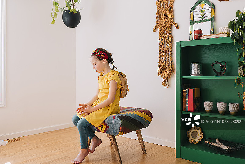 女孩坐在凳子上拿着金色礼品券的肖像图片素材