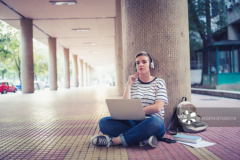 学生生活：课后坐在大学前的女学生图片素材