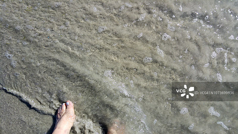 南非开普敦，白人女性在海浪中的脚部俯视图图片素材