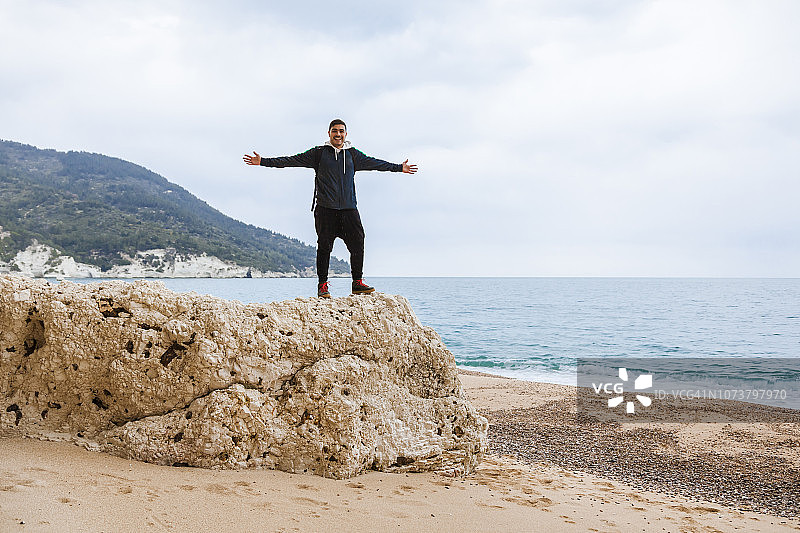 意大利维耶斯泰：男子在维尼亚诺蒂卡海滩的岩石上放松身心，张开双臂图片素材
