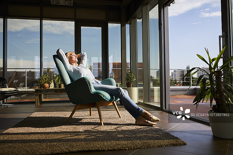 中年妇女在家中阳光下躺在扶手椅上放松图片素材