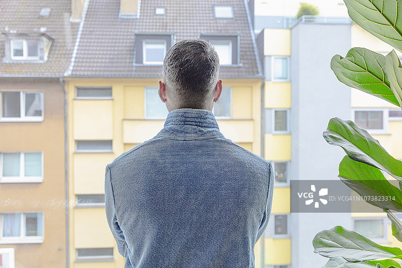 男人看着窗外的公寓楼图片素材