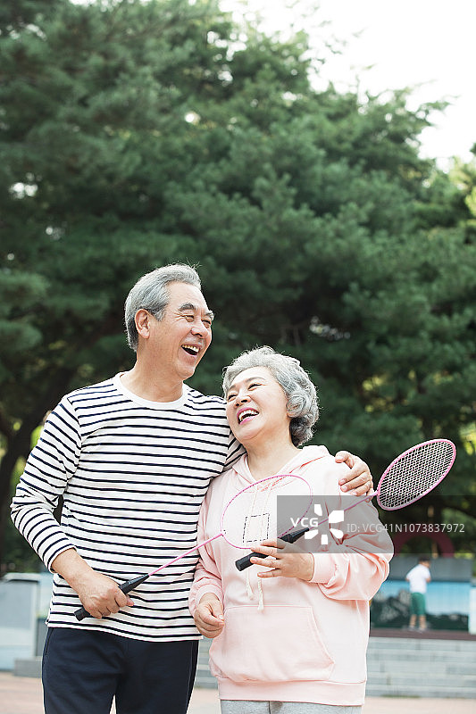 老年夫妇在公园里笑着打羽毛球图片素材