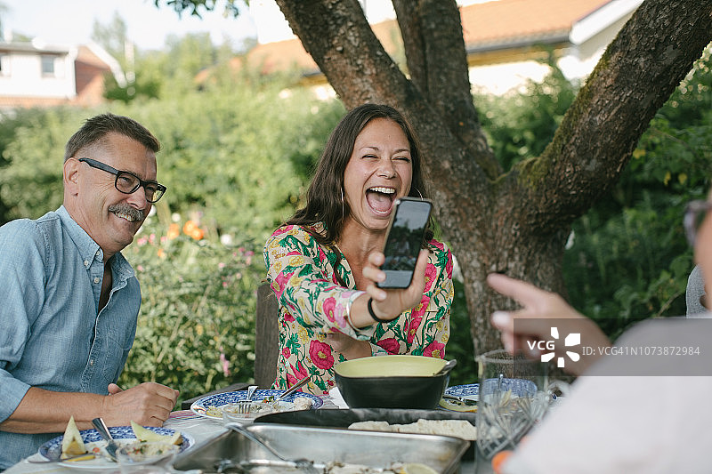 花园聚会上，年轻女人向年长的女人展示智能手机图片素材