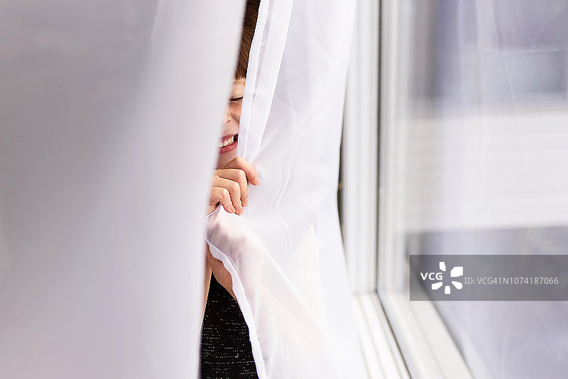 躲在窗帘后面笑的女孩图片素材