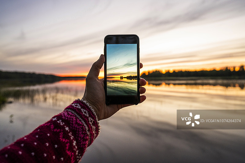 芬兰卡亚尼，人用智能手机拍日落图片素材