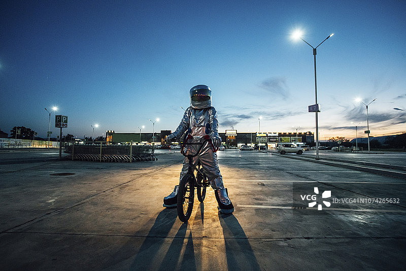 夜晚城市停车场骑BMX自行车的宇航员图片素材