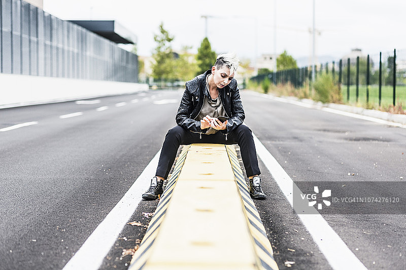 坐在路边用手机的朋克女性图片素材