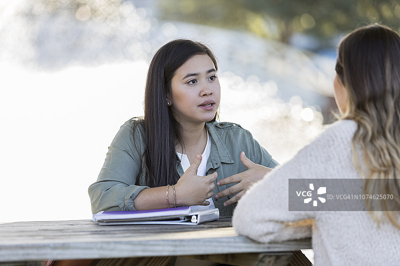 年轻女人与大学同学在户外交谈图片素材