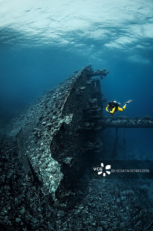 水肺潜水员观察覆盖珊瑚的红海海底沉船图片素材