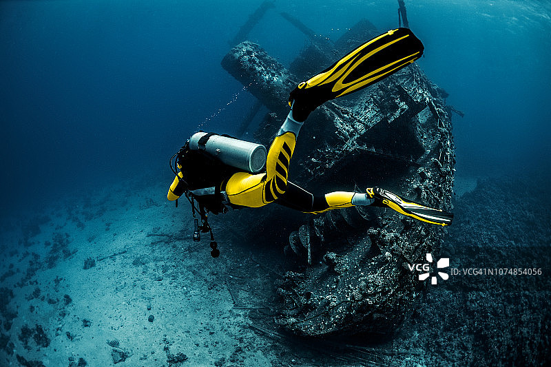 在红海中围绕着生锈的旧水下沉船潜水的水肺潜水员图片素材