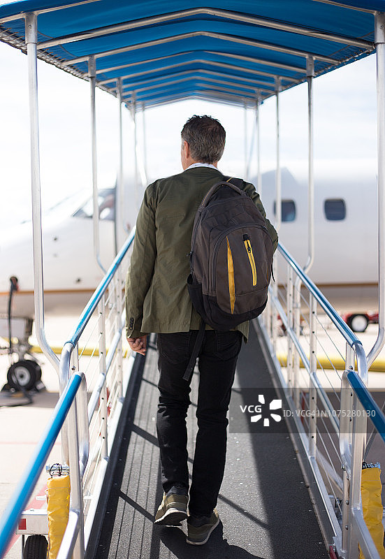 背着背包的老年人在户外斜坡上登上小型飞机图片素材