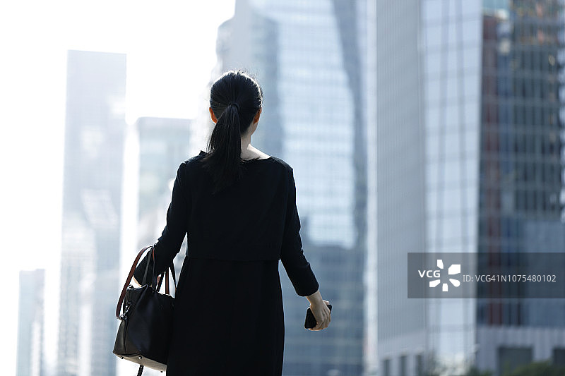 女子站在城市背景下眺望远方的背影图片素材
