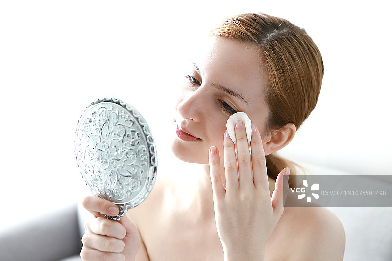 女人用化妆棉将清洁乳液涂在脸上图片素材
