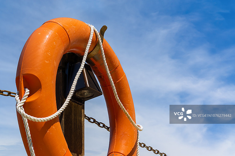 阳光明媚的蓝天下橙色救生圈图片素材