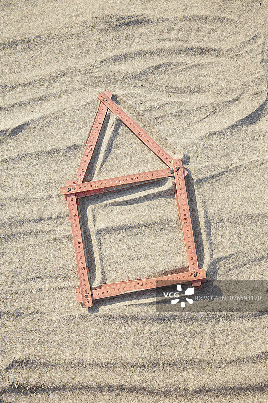 沙地/建筑工地上红色折叠尺组成的房屋形状俯视图片素材