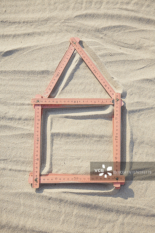 沙地/建筑工地上红色折叠尺组成的房屋形状俯视图片素材