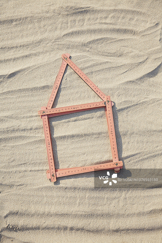 沙地/建筑工地上红色折叠尺组成的房屋形状俯视图片素材