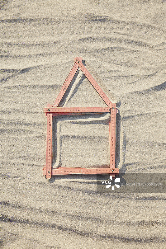 沙地/建筑工地上红色折叠尺组成的房屋形状俯视图片素材