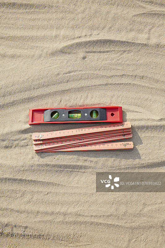 红色折叠尺和水平仪在沙地/建筑工地的高角度视图图片素材