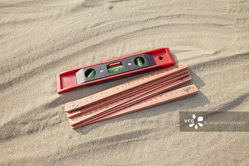 红色折叠尺和水平仪在沙地/建筑工地的高角度视图图片素材