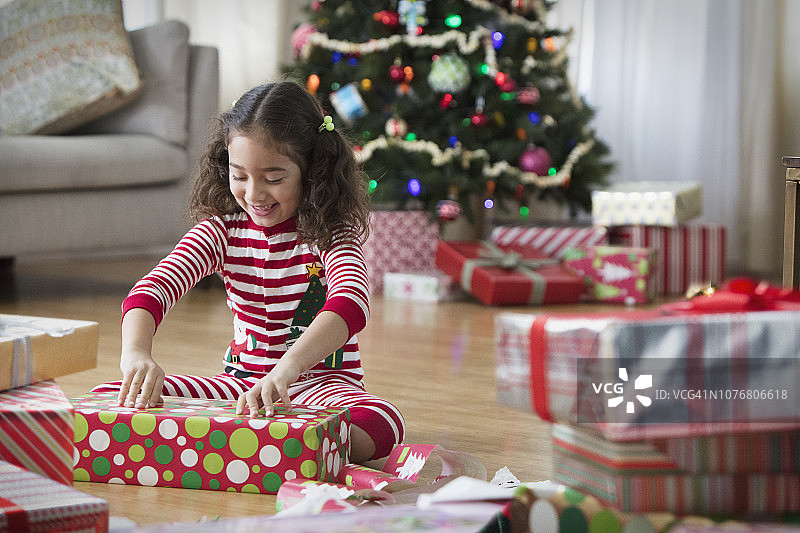 小女孩在客厅里打开圣诞礼物图片素材