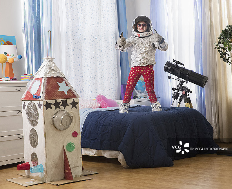 站在床上玩纸板火箭的年轻女孩图片素材