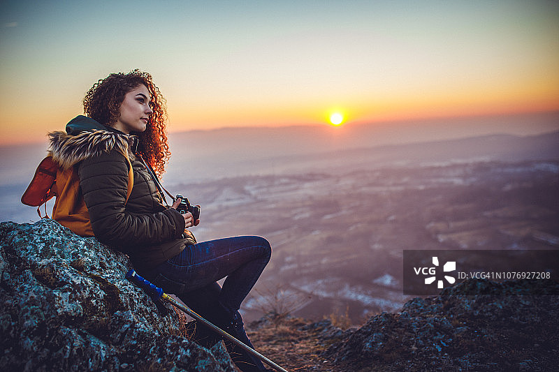 卷发年轻女性在山顶上观看日落图片素材