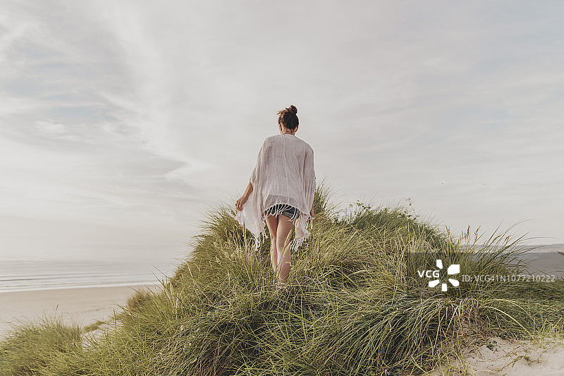 站在康沃尔郡Gwithian Towans海滩沙丘顶上享受夏末阳光的女人图片素材