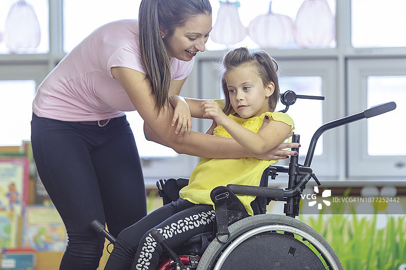 老师帮助坐轮椅的小女孩图片素材