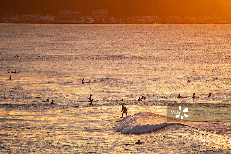 日本神奈川县镰仓市橙色海滩上的冲浪者图片素材