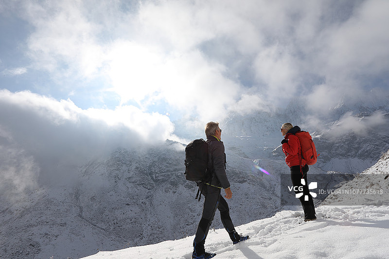 徒步情侣登上雪山山脊图片素材