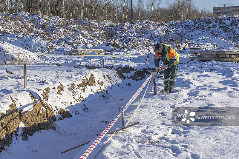 建筑工地上的工人用信号带屏蔽沟槽，用于地籍测量图片素材