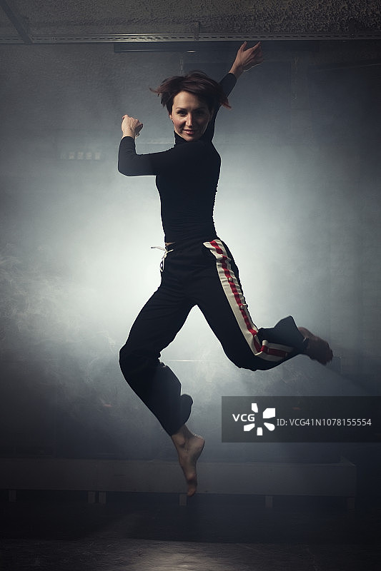 身着黑色服装的现代舞者在烟雾缭绕的演播室里摆姿势图片素材