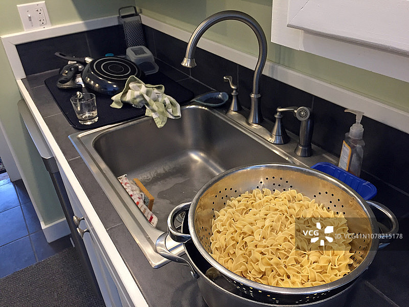 厨房水槽旁的金属过滤器中的螺旋面图片素材