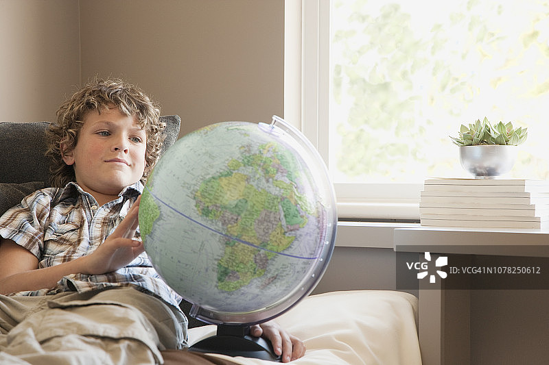 男孩在卧室里看地球仪图片素材