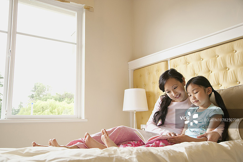 亚洲母亲和女儿在床上读书图片素材