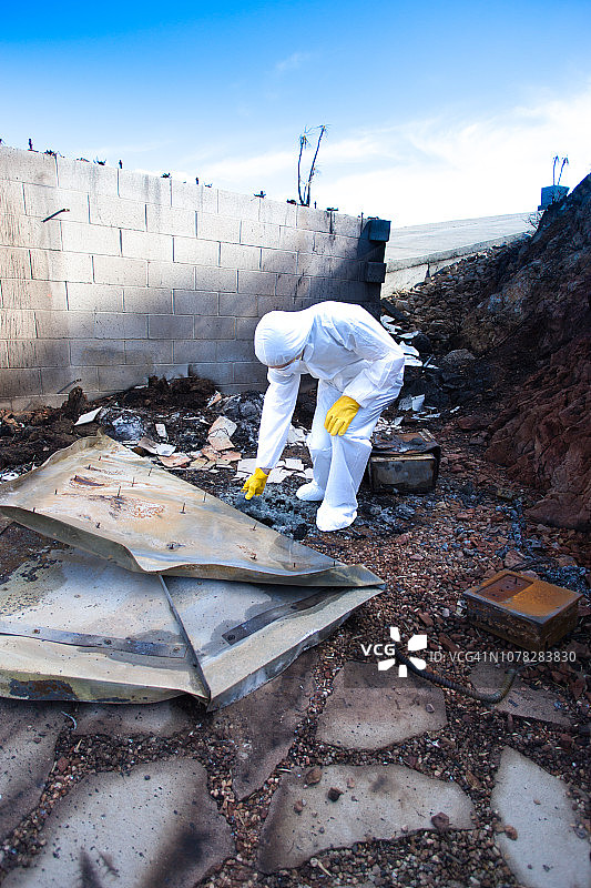 穿防护服的男人在野火废墟中翻找图片素材