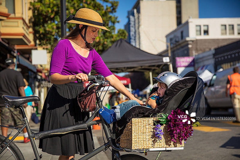 妈妈在农贸市场查看绑在货运自行车上的幼儿图片素材