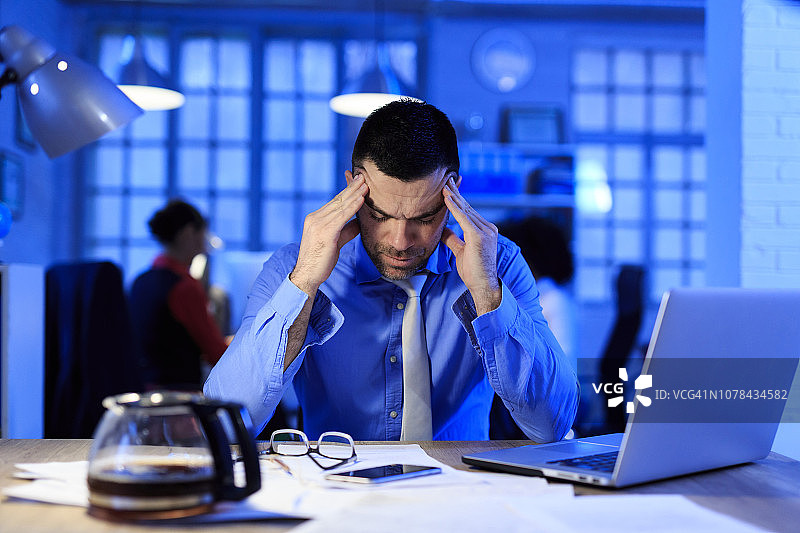 中年商人工作到深夜，遇到问题图片素材