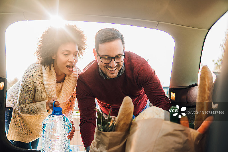 微笑的夫妇在车里装杂货图片素材