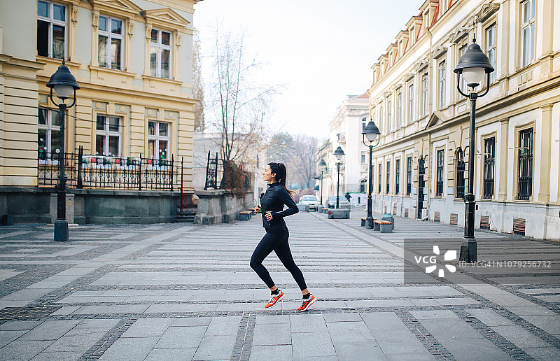 在城市街道上跑步的年轻女人图片素材