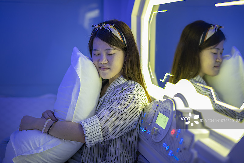 中国女性在胶囊旅馆的床上抱着枕头图片素材