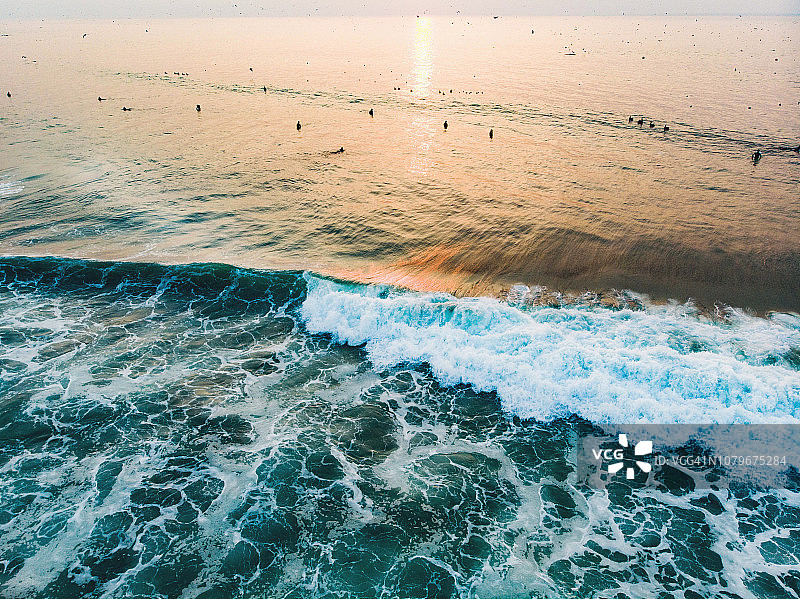 日落时分在旧金山海滩乘浪的冲浪者图片素材