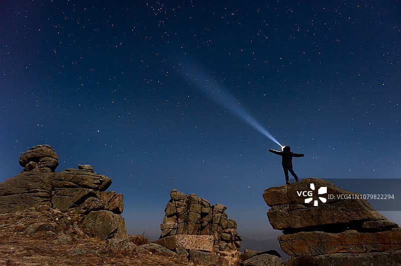 一个人站在有车头灯的银河系旁边图片素材