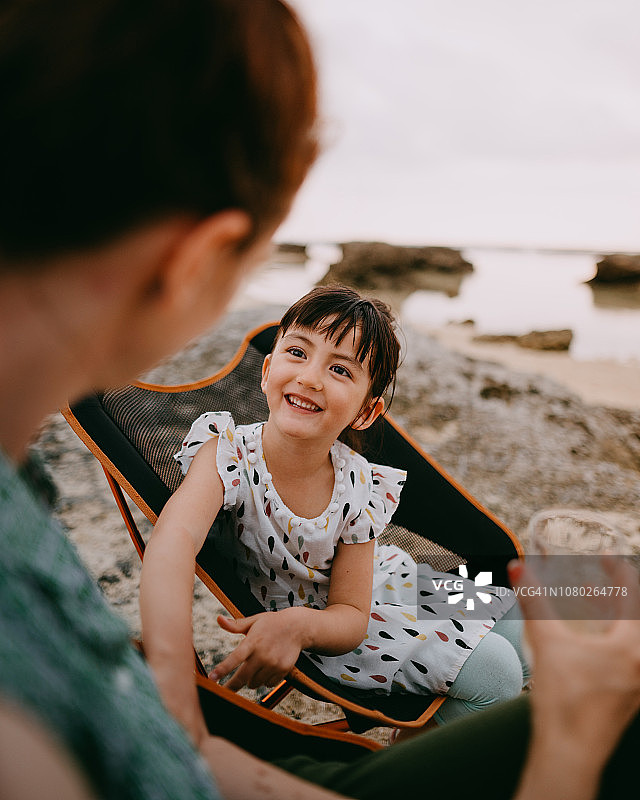 可爱的小混血女孩在海滩上对着母亲微笑图片素材