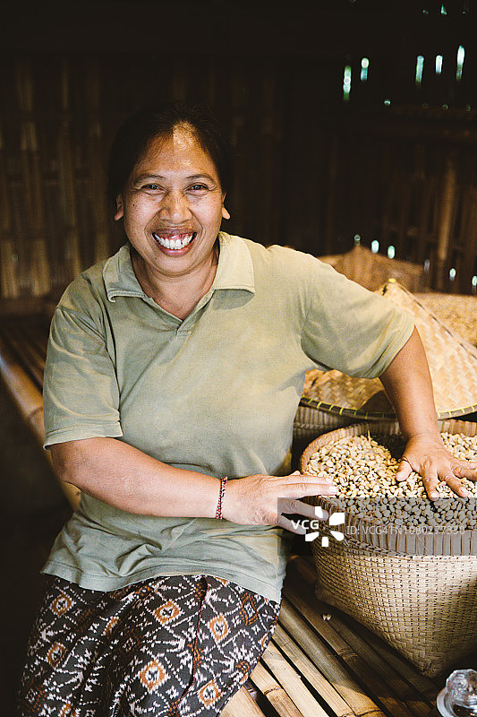 在巴厘岛以传统方式烘焙咖啡豆的印尼女人图片素材