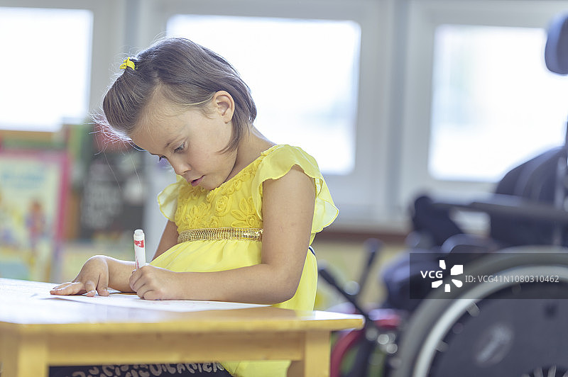 在桌子旁画画的残疾儿童图片素材