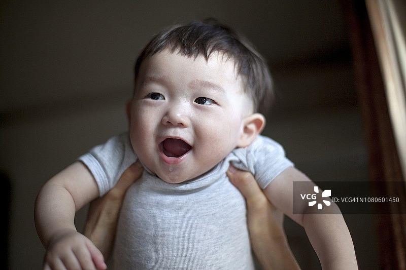 被母亲抱起，欢快地笑着的小男婴图片素材
