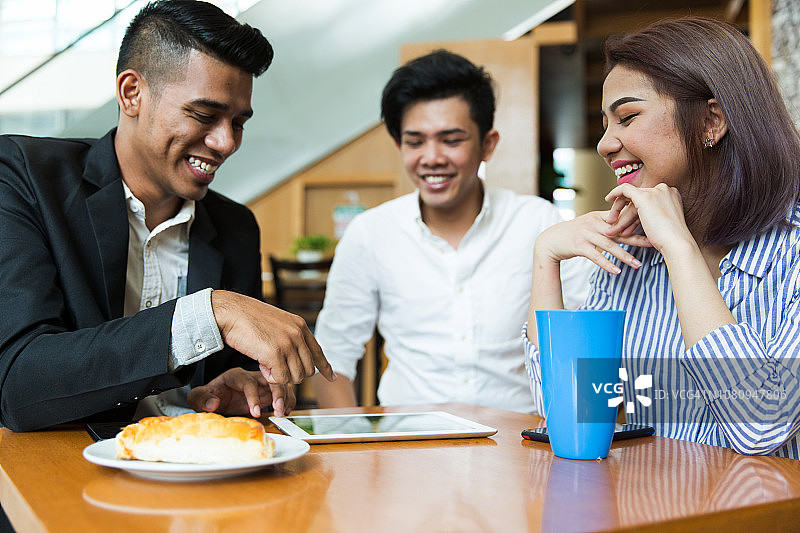 三个朋友在咖啡馆用笔记本电脑会面图片素材